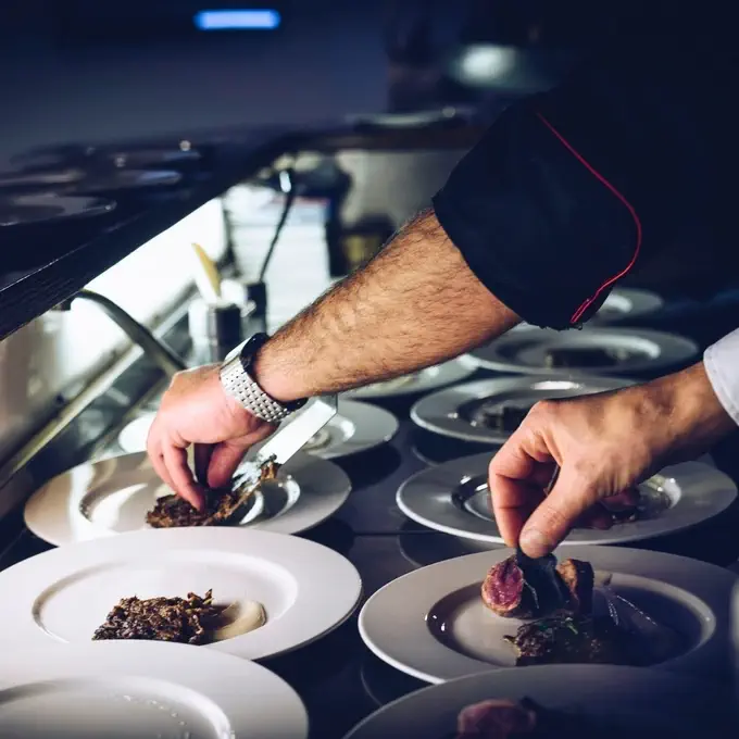Catering staff plating meals in a professional kitchen.